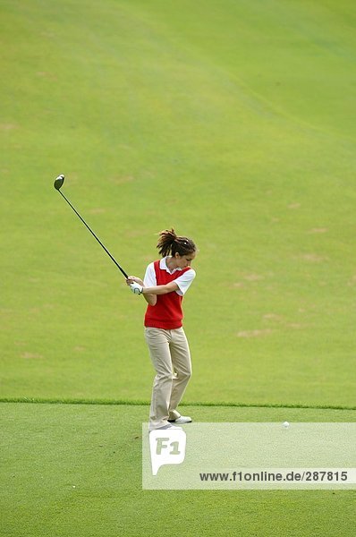 Weibliche Golfer nehmen eine Schaukel auf dem Boden tee