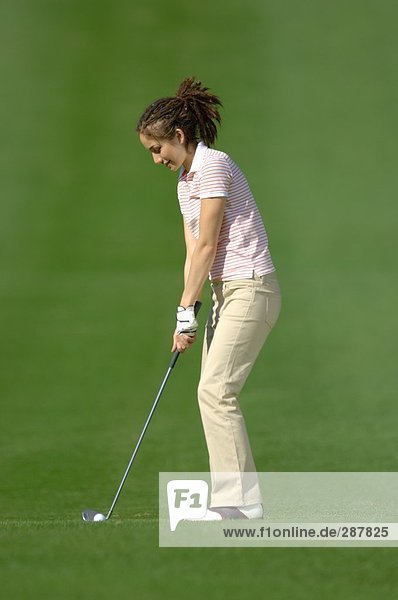 Eine weibliche Golfer vorbereiten  ihre Ball getroffen