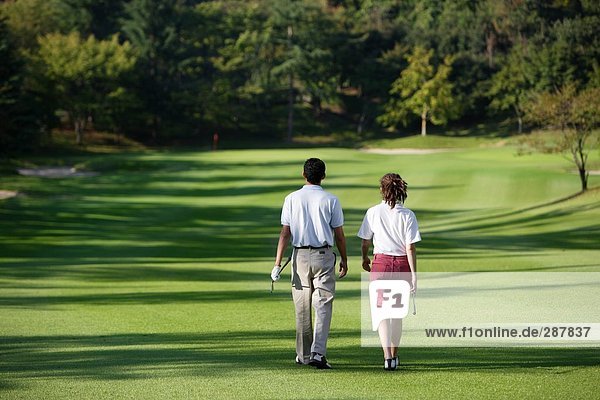 Rear view of a couple walking down the fairway