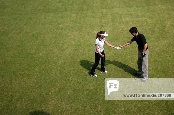 Man passing a golf ball to a woman
