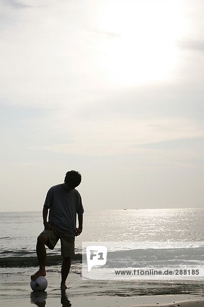 Silhouette Of a Young Man With a Soccer Ball on the Beach