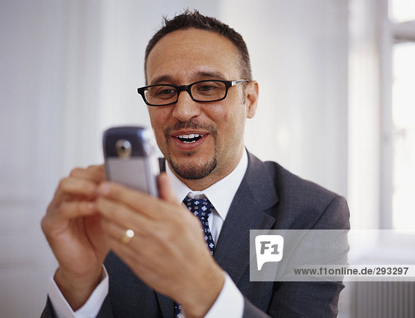 Ein lächelnd mann mit einem Mobiltelefon.