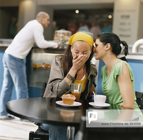 Two women laughing in a cafe.