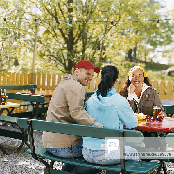 Drei Freunde in ein open-air-Restaurant.