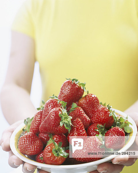 Eine Person  der eine Schüssel gefüllt mit Erdbeeren.