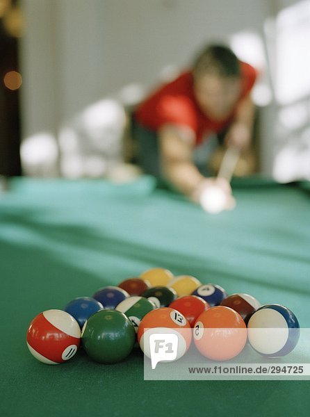 Billiard Balls auf einen Billardtisch  von einem Mann im Hintergrund gespielt werden.