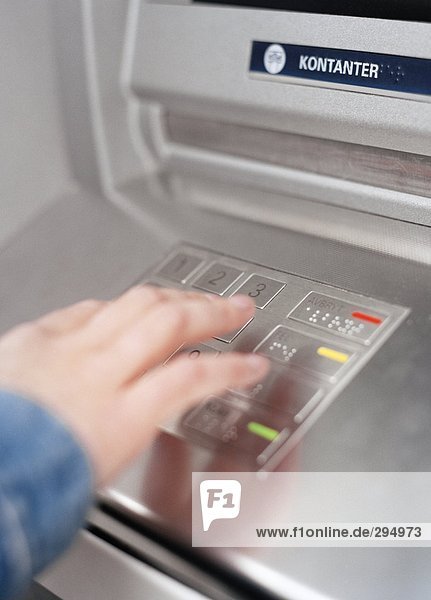 Eine Person seinen Code in Geldautomaten-einfügen.