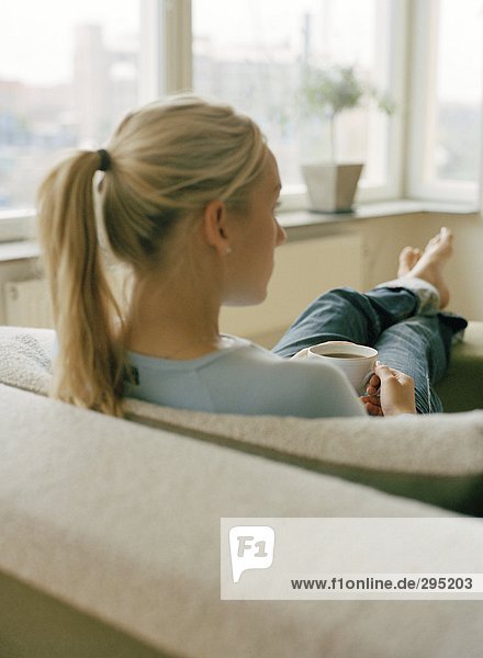 Eine Frau in einem Sofa Rückansicht sitzend.