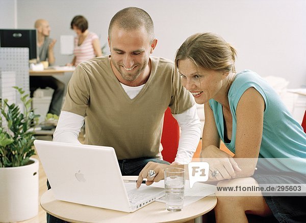A woman and a man sitting in front of a computer.