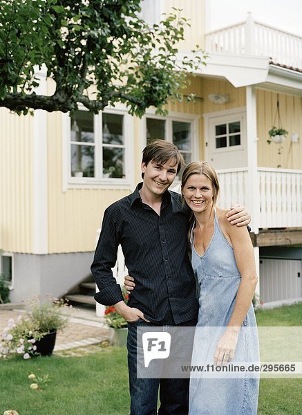 A couple embracing in a garden smiling.