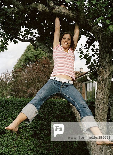 A woman hanging in a tree branch.