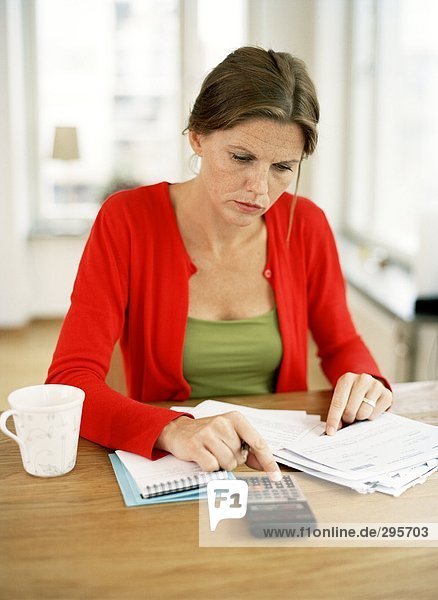 Eine Frau mit einem Rechner und Rechnungen.
