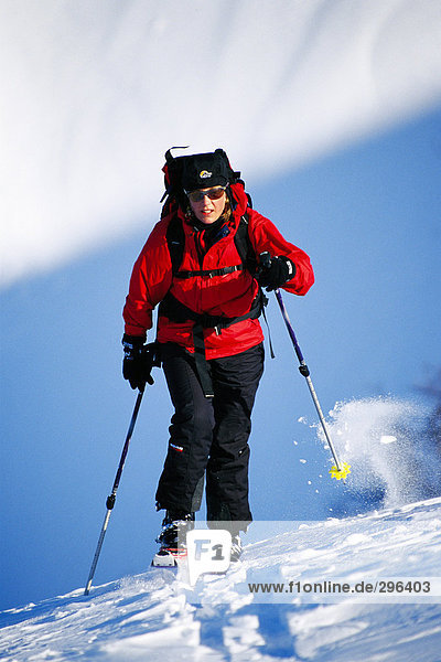 Eine weibliche Skifahrer auf dem Weg bis auf eine Piste.