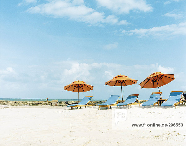 Liegestühle und Sonnenschirme am Strand.