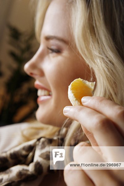 Eine Frau essen eine orange Keil.