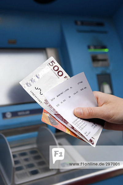 Cash-Dispenser mit Kreditkarte und Geld hält hände.