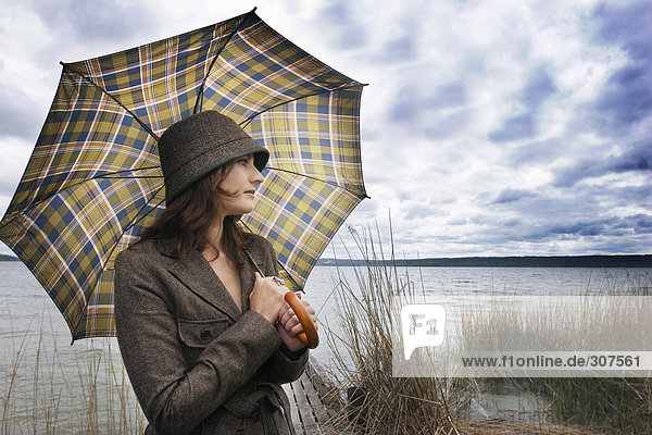 Junge Frau hält Regenschirm  schaut weg
