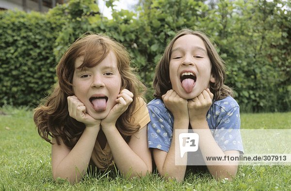 Children lying in meadow in garden portrait