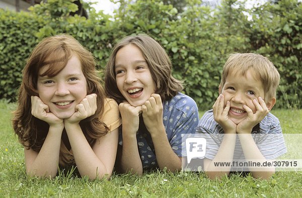Children lying in meadow in garden portrait