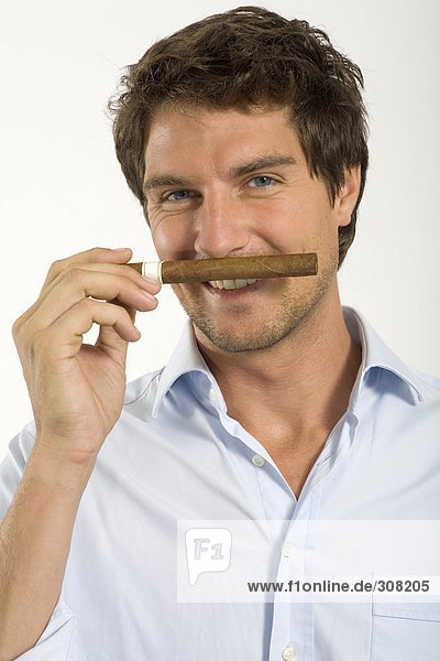 Young man smelling cigar  close-up  portrait