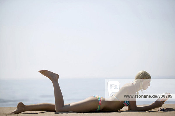 Frau entspannt am Strand  Lesebuch  Seitenansicht