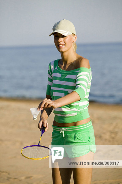 Junge Frau spielt Badminton am Strand