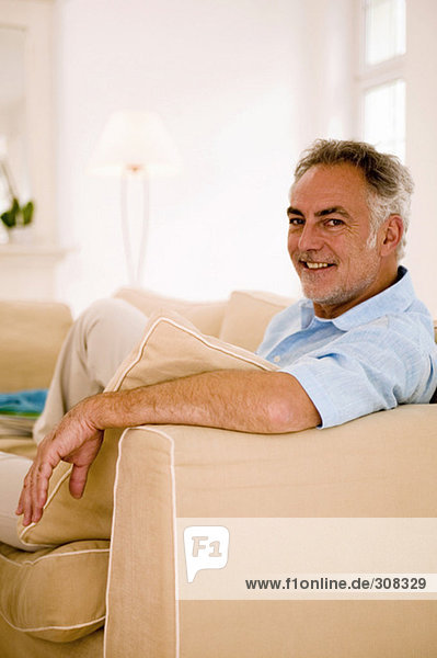 Mature man sitting on sofa in living room  portrait  close-up
