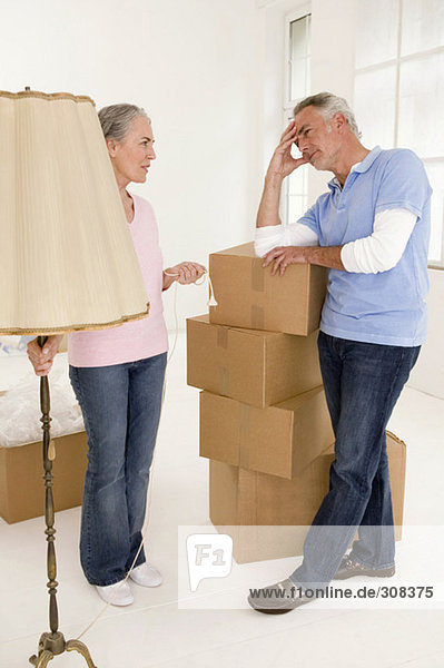 Erwachsenes Paar im Wohnzimmer mit Pappkartons  diskutiert über
