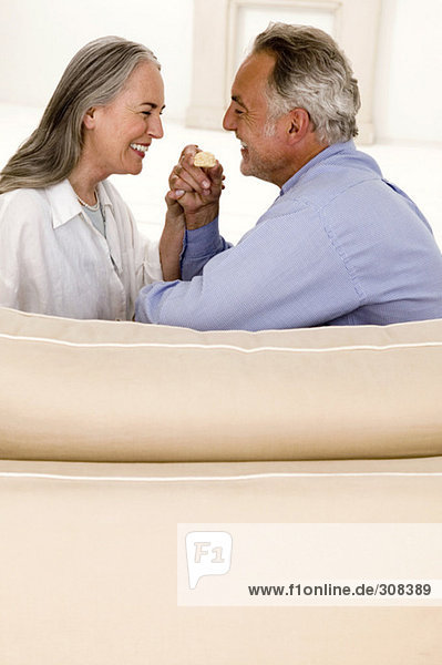 Erwachsenes Paar auf dem Sofa sitzend  lächelnd  Seitenansicht