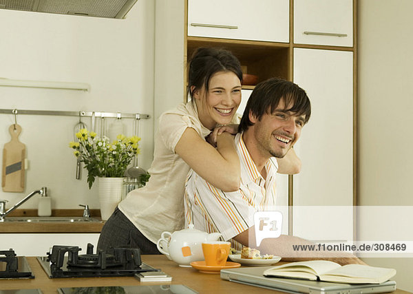 Junges Paar in der Küche  wegschauend  lächelnd