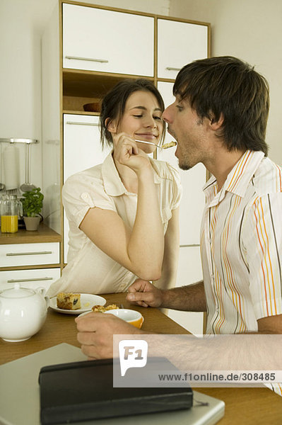 Junges Paar in der Küche  Frau füttert Mann
