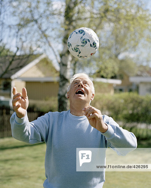 Ein älterer Mann mit einem Fußball spielen.