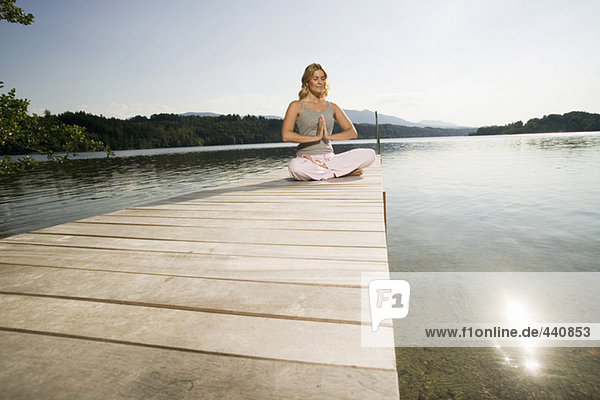 Woman exercising yoga on jetty