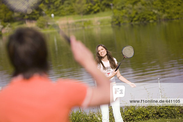 Young couple playing badminton  focus on woman