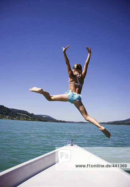 Teenagermädchen (13-15) springt vom Boot ins Wasser,  Rückansicht
