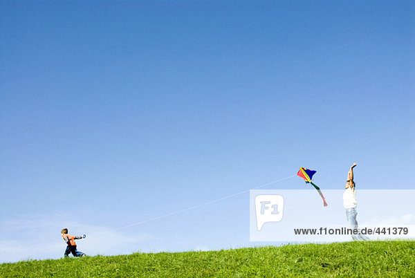 Father and son (4-7) flying kite in park  side view