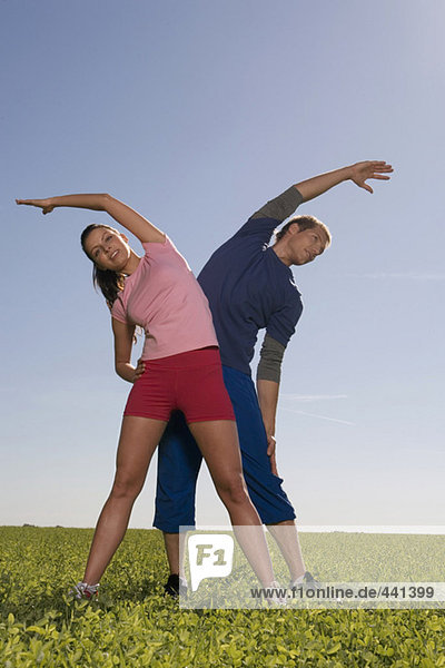 Junges Paar beim Gymnastizieren auf der Wiese