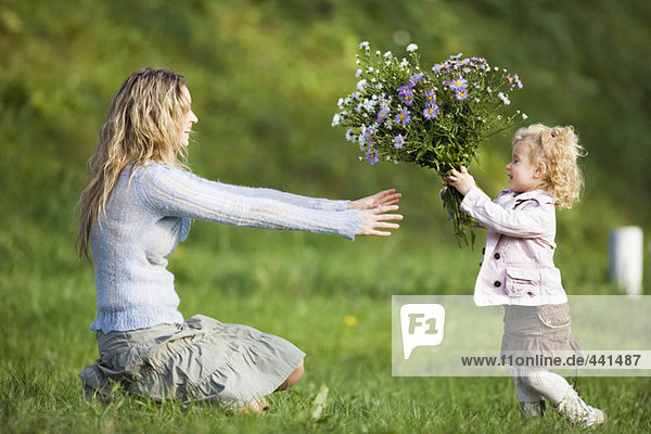 Tochter schenkt Mutter Blumenstrauß,  Seitenansicht