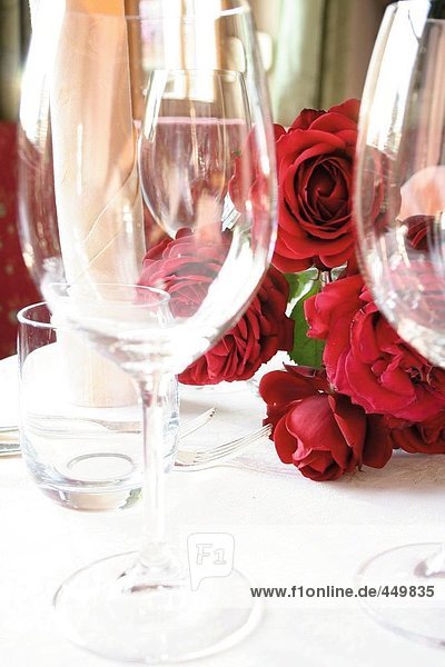 Stem glasses and bunch of roses on table