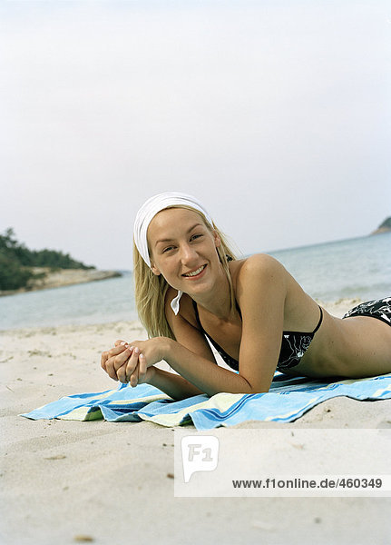 A woman sunbathing on a beach.