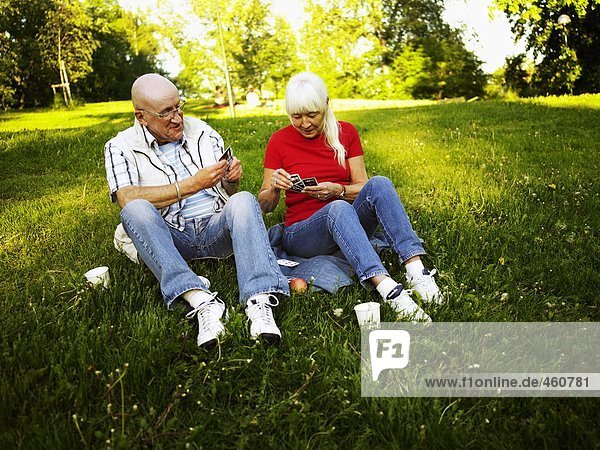 A couple playing cards outdoors.