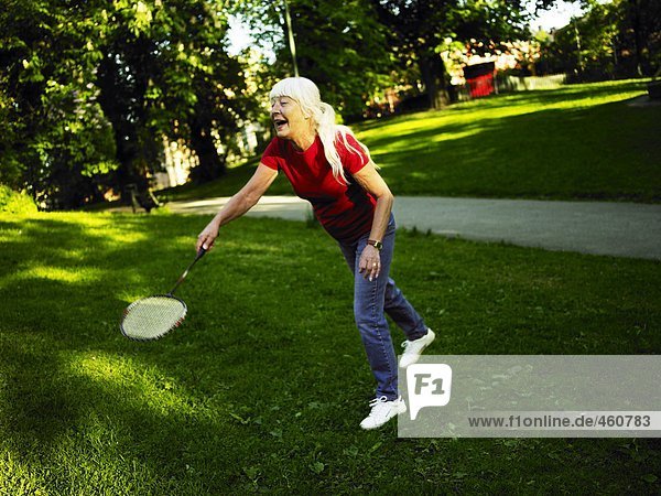 A woman playing badminton outdoors.