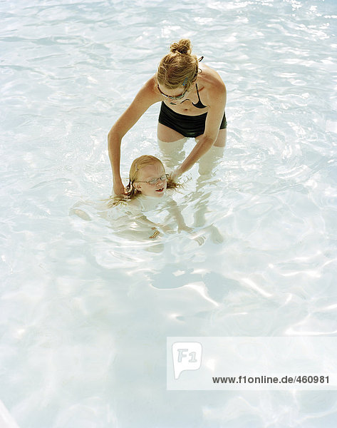 Eine Mutter ihre Tochter schwimmen unterrichten.