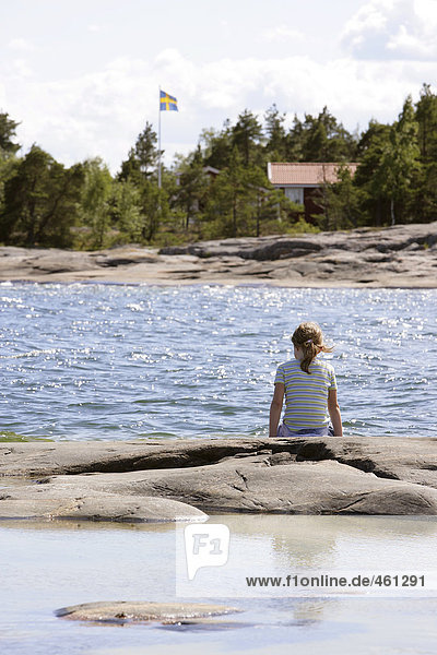 A girl sitting on a cliff in the archipelago.