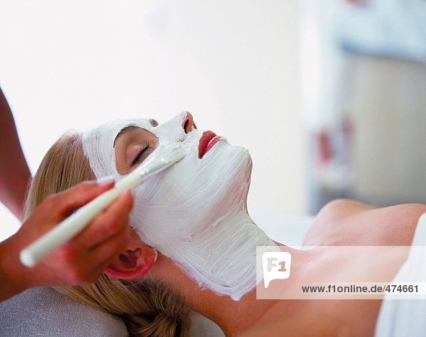 Weibliche Therapeut Gesichtscreme auf junge Frau Gesicht Umsetzung