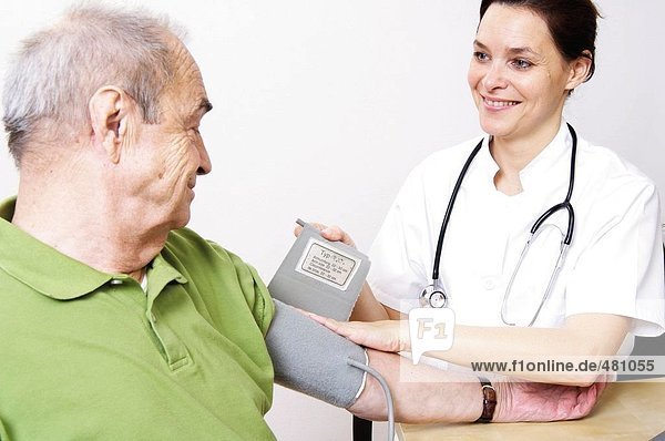 Female Nurse Überprüfung des Mannes Blutdruck