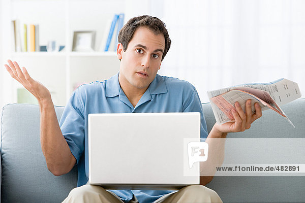 Man with bills and a laptop computer