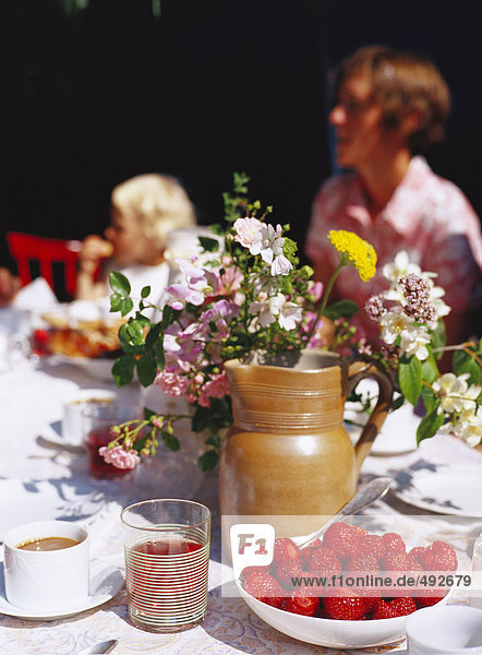 Erdbeeren und Blumen auf dem Tisch.