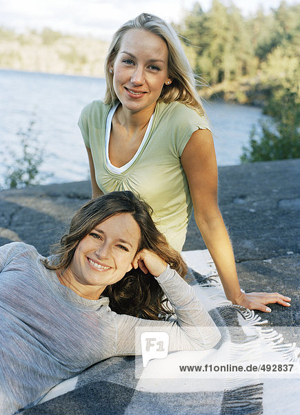 Zwei junge Frauen an einem See.