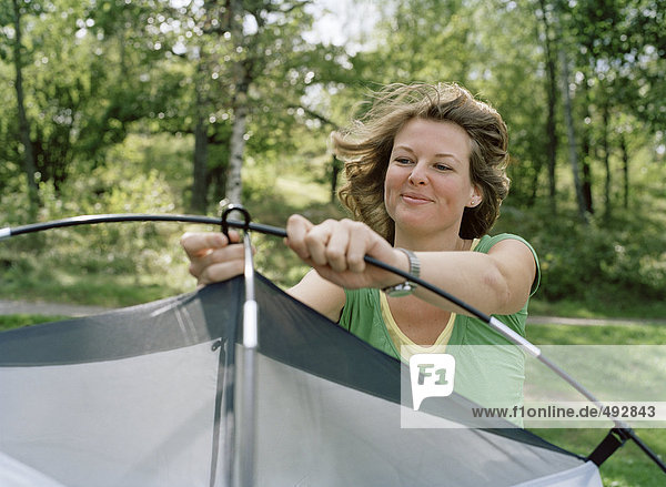 A woman setting up a tent.